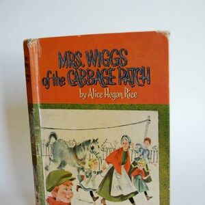 May include: A vintage book cover with an orange background and green border. The title is "Mrs. Wiggs of the Cabbage Patch" by Alice Hegan Rice. The cover features an illustration of a woman and children walking with a horse.