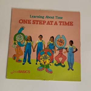 May include: A colorful book cover with the title "Learning About Time ONE STEP AT A TIME" and a group of children holding hands with clock characters. The book is from the Upbeat Basics series.