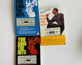 May include: Three cassette tapes with colorful covers featuring the text "You Sing The Hits". Each tape includes a different artist: Duke Ellington, Nat "King" Cole, and Great Standards. The tapes are labeled with the song titles and include instructions for using the tapes with a cassette player.