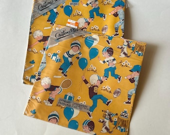May include: Two packages of mustard yellow gift wrap featuring a repeating pattern of children playing sports, including baseball, football, and hockey. The paper displays blue balloons, white flowers, and the text Creations Plus.