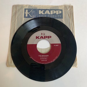 May include: A black vinyl record with a red and white label. The label says "KAPP" and "K-266X". The record is titled "Two Brothers" by David Hill. The record is manufactured by Kapp Records, Inc. in New York.