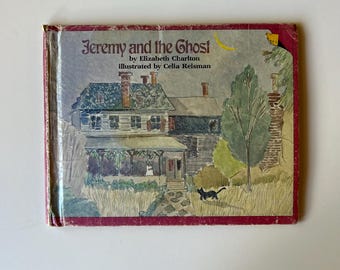 May include: A hardcover children's book titled Jeremy and the Ghost by Elizabeth Charlton, illustrated by Celia Reisman. The cover features a watercolor illustration of a house, a tall tree, a black cat, and a yellow crescent moon.