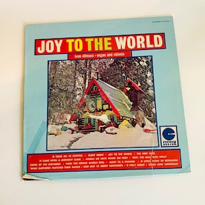 May include: A vintage vinyl record album cover featuring a snowy winter scene with a small, red-roofed house. The album title is "Joy to the World" with the artist "Ivan Ditmars - organ and chimes". The album cover features a custom record label.