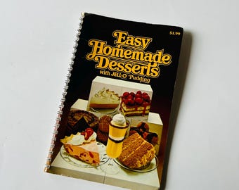May include: A vintage cookbook titled "Easy Homemade Desserts with JELL-O Pudding" with a price tag of $1.99. The cover features a colorful illustration of various desserts, including a pie, cake, and pudding.