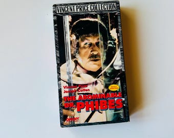 May include: A rectangular VHS tape case for The Abominable Dr. Phibes, part of the Vincent Price Collection. The cover features a portrait of Vincent Price, the title in bold red and blue lettering, and a yellow Digitally Remastered burst.