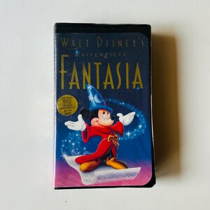 May include: A sealed VHS tape of Walt Disney's Fantasia. The cover features Mickey Mouse in a sorcerer's outfit, with the title in gold lettering. The background is a starry, blue gradient. The tape is in its original packaging.