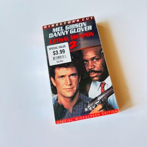 May include: A VHS tape of the movie "Lethal Weapon 2" featuring Mel Gibson and Danny Glover. The cover has a red and blue color scheme with the movie title prominently displayed. The tape is a special widescreen edition.
