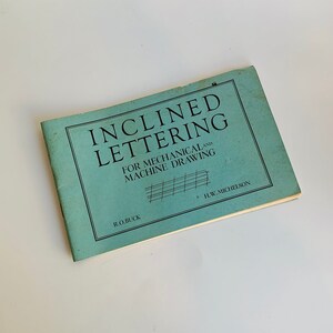 May include: A blue booklet titled "Inclined Lettering for Mechanical and Machine Drawing" by R.O. Buck and H.W. Michelson.