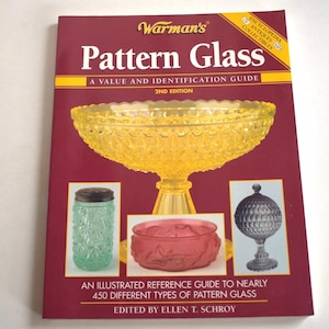 May include: A red book titled "Warman's Pattern Glass: A Value and Identification Guide, 2nd Edition". The book cover features a yellow glass bowl, a green glass jar, a red glass bowl, and a gray glass ball on a stand.