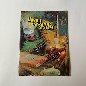 May include: A vintage book cover titled "The Soviet Transport System" featuring illustrations of a train, rocket, and classic car. The cover has a retro design with a mix of red, orange, and blue hues.