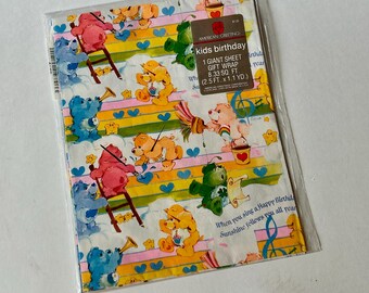 May include: A folded sheet of gift wrap in a clear plastic sleeve featuring Care Bears characters, rainbows, and musical notes. A brown label reads American Greetings kids birthday 1 giant sheet gift wrap 8.33 sq. ft. (2.5 ft. x 1.1 yd.).
