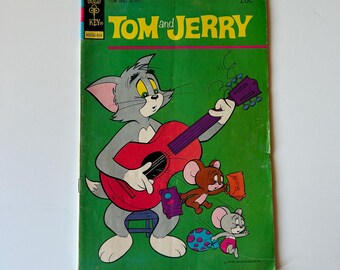 May include: A vintage Tom and Jerry comic book with a green cover featuring Tom the cat playing a red acoustic guitar. Jerry the mouse and another small mouse are depicted nearby with luggage and a polka-dot ball. The text reads Gold Key and 20c.