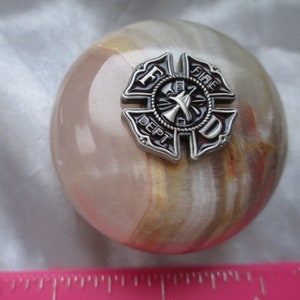 May include: A round, white, brown, and orange marble paperweight with a silver metal firefighter emblem. The emblem has the letters F.D. and the word "FIRE DEPT."