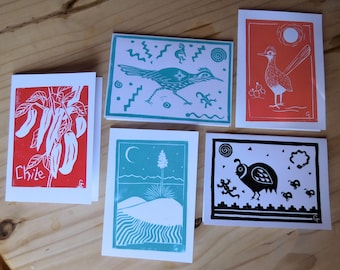 May include: Five greeting cards with different designs. The cards are white with a red, blue, or black border. The designs include a chili pepper plant, a bird, a desert scene, and a quail. The text "Chile" is printed on one of the cards.