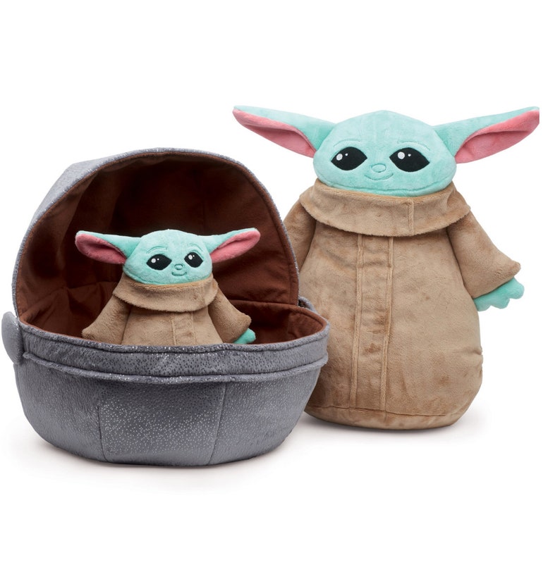 May include: Two plush toys of the character "The Child" from the Star Wars series "The Mandalorian". The larger plush toy is standing and wearing a brown robe. The smaller plush toy is sitting inside a gray egg-shaped pod.