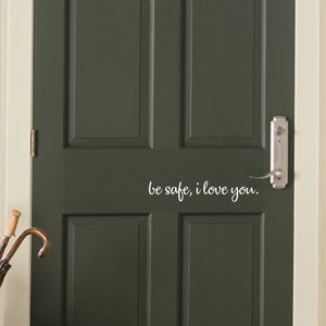 May include: A dark green front door with a glass panel above the door. The door has a white vinyl decal that reads "Be safe, I love you."