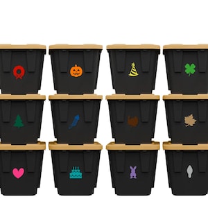May include: Twelve black storage bins with tan lids, each decorated with a different colorful icon. Icons include a wreath, pumpkin, party hat, shamrock, Christmas tree, firework, turkey, leaf, heart, cake, bunny, and a footprint.