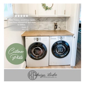 May include: White washing machine and dryer with black vinyl decals that say "Wash" and "Dry" in a wreath design. The decals are placed on the front of the appliances.