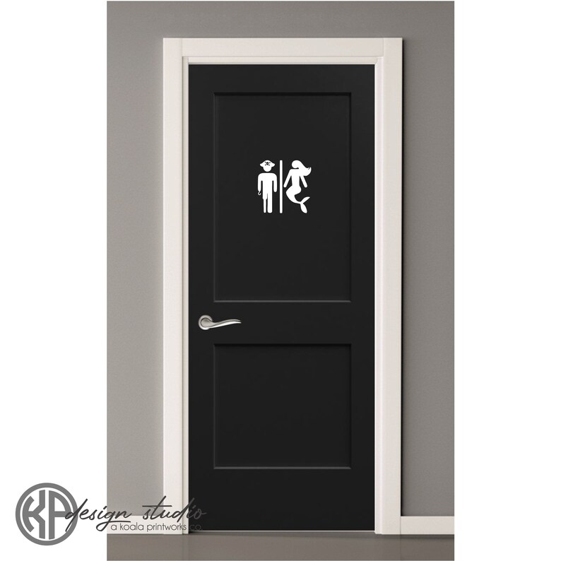 May include: A black door with a white sticker of a sailor and a mermaid on it. The sticker is a bathroom sign.