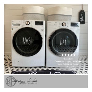 May include: White washer and dryer with black text that says "WASH" and "DRY" on the front. The washer and dryer are in a white tiled laundry room with a black and white patterned rug.