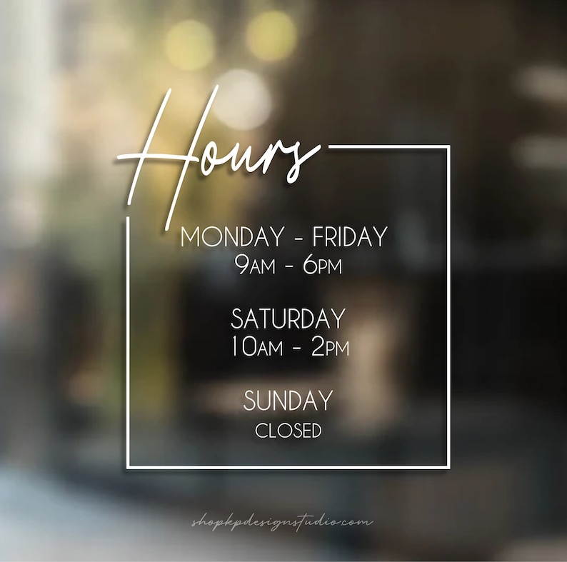 May include: A white sign with black text outlining business hours. The sign says "Hours" in a cursive font. The hours are: Monday - Friday 9AM - 6PM, Saturday 10AM - 2PM, Sunday Closed. The website shopkpdesignstudio.com is listed at the bottom.