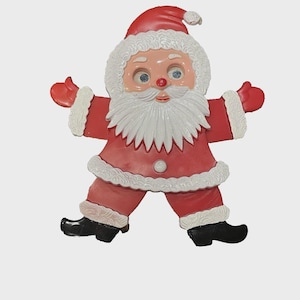 May include: A vintage Santa Claus decoration in a cheerful pose. The figure is primarily red with white trim and a white beard. Santa's face is detailed with blue eyes and a rosy nose. Black boots complete the festive look.