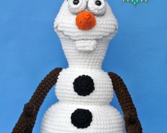 May include: A handmade crochet Olaf doll from the movie Frozen. The snowman has a white body with black button accents, a carrot nose, and brown stick arms and hair. The doll is on a blue background. The Whole Knit Caboodle logo is in the upper right corner.