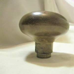 May include: A vintage brass door knob with a rounded oval shape. The knob has a smooth, polished finish and a simple design.