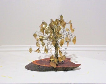 May include: A gold wire tree sculpture with leaves made of gold foil. The tree is mounted on a wooden base.