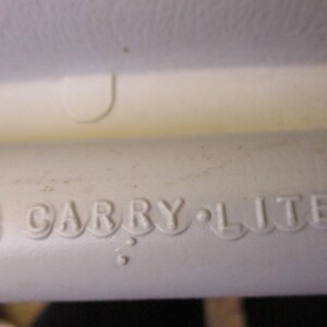 May include: Close-up of a white plastic object with the words "Carry-Lite" embossed on the side.