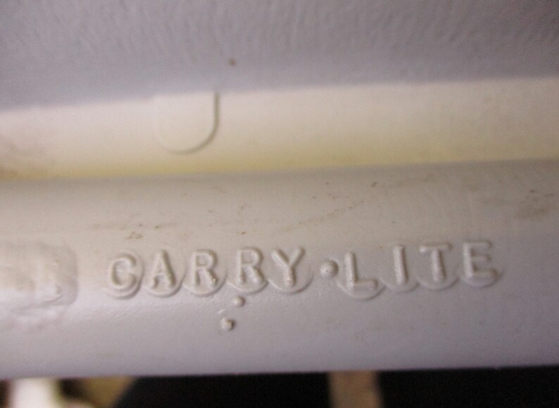 May include: Close-up of a white plastic object with the words "Carry-Lite" embossed on the side.