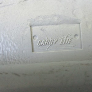 May include: Close-up of a white label with the text "CARRY LITE" in black lettering.