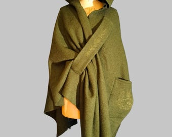 May include: Olive green hooded cloak with a large hood and a front pocket. The cloak is draped over a mannequin, showcasing its flowing design. The fabric appears to be a soft, textured material.