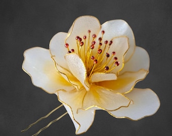 May include: A white and gold flower hair comb with red beads in the center. The comb is made of wire and fabric.