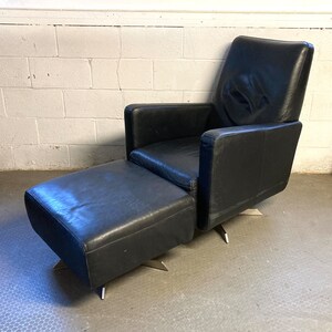 May include: A black leather armchair with a matching ottoman. Both pieces have a modern design with a swivel base.