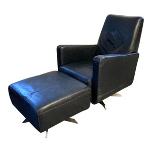 May include: A black leather armchair with a matching ottoman. Both pieces have a swivel base and are upholstered in a smooth, dark leather.
