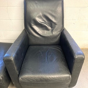 May include: A black leather armchair with a high back and a swivel base. The chair has a simple, modern design.