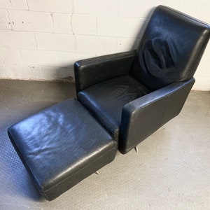 May include: A black leather armchair with a matching ottoman. The chair has a high back and a swivel base.