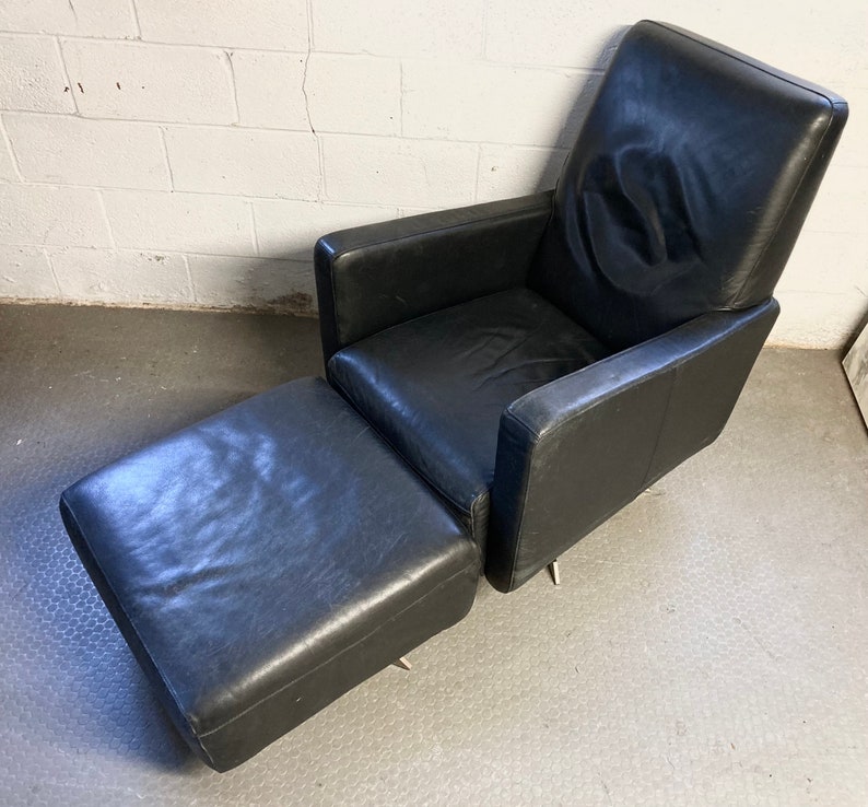 May include: A black leather armchair with a matching ottoman. The chair has a high back and a swivel base.