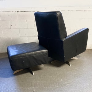 May include: A black leather armchair and ottoman with a swivel base and silver metal legs.