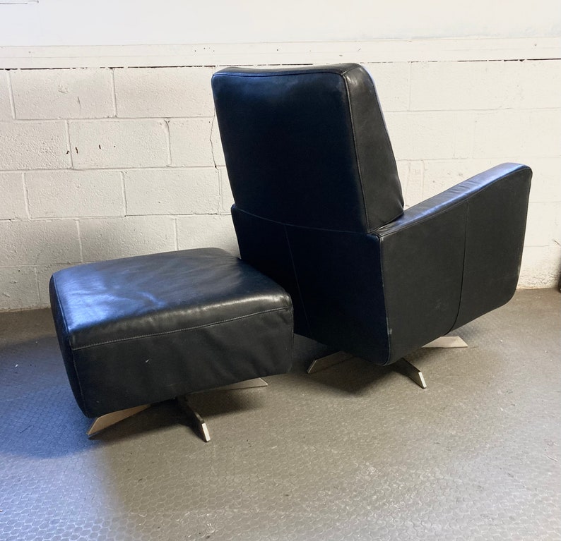 May include: A black leather armchair and ottoman with a swivel base and silver metal legs.