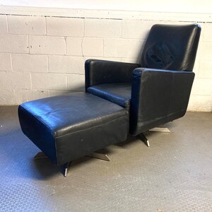 May include: A black leather armchair with a matching ottoman. Both pieces have a swivel base and are upholstered in a dark leather.