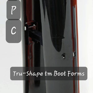Könnte beinhalten: Zwei schwarze Kunststoff-Stiefelformen zum Formen von Schuhen. Die Formen sind gebogen und haben eine glatte, glänzende Oberfläche. Der Text "Tru-Shape tm Boot Forms" und "#395/9" ist auf dem Bild sichtbar.
