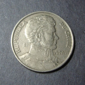 May include: A silver coin with the text "REPUBLICA DE CHILE" and a portrait of a man on the front.
