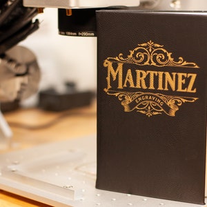 May include: A black leather-bound journal with gold lettering that reads "Martinez Engraving".