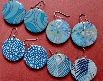 Op de afbeelding: Acht paar blauwe en witte gepatroneerde oorbellen met zilveren haakjes. De oorbellen zijn rond en hebben verschillende ontwerpen, waaronder stippen, paisley en abstracte patronen.