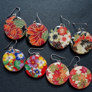 May include: A set of eight earrings featuring round, colorful, patterned designs. The earrings are made with Japanese paper and have silver hooks.