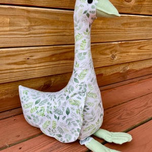 Peluche gigante de ganso de felpa cosido a mano en color verde salvia y blanco.