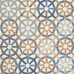 Op de afbeelding: Een quilt met een geometrisch patroon in bruin, blauw en wit. De quilt is gemaakt van veel kleine vierkanten die aan elkaar zijn gestikt om een groter ontwerp te cre&euml;ren.