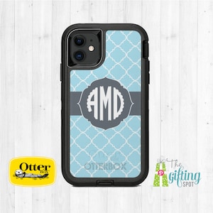 May include: A black Otterbox phone case with a blue and white geometric pattern. The case has a gray band with the monogram "AMD" in white. The case is for an iPhone.